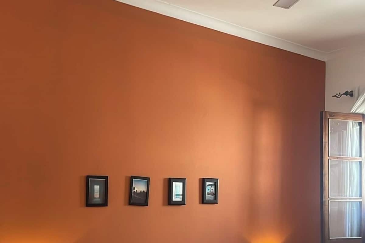 A bedroom with a bed, two bedside tables, a ceiling fan, and four framed pictures on the wall.