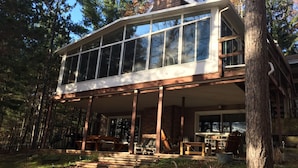 Una casa moderna con ventanas amplias, un porche cubierto y una chimenea de ladrillo.
