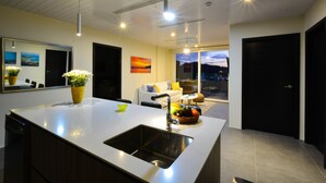 A modern kitchen with a large island, a built-in sink, and a dining area with a sofa and a table. - 2 Bedroom Apartment, Private Pool - Luna 03 (SAn Juan del Sur)