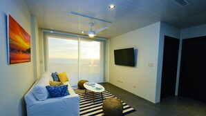 A modern living room with a sofa, pillows, a coffee table, and a large window. - 2 Bedroom Apartment, Private Pool - Luna 03 (SAn Juan del Sur)