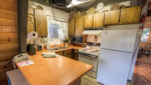 Une cuisine de taille réduite, dotée de meubles en bois, d’un four à micro-ondes, d’une cuisinière et d’un réfrigérateur.