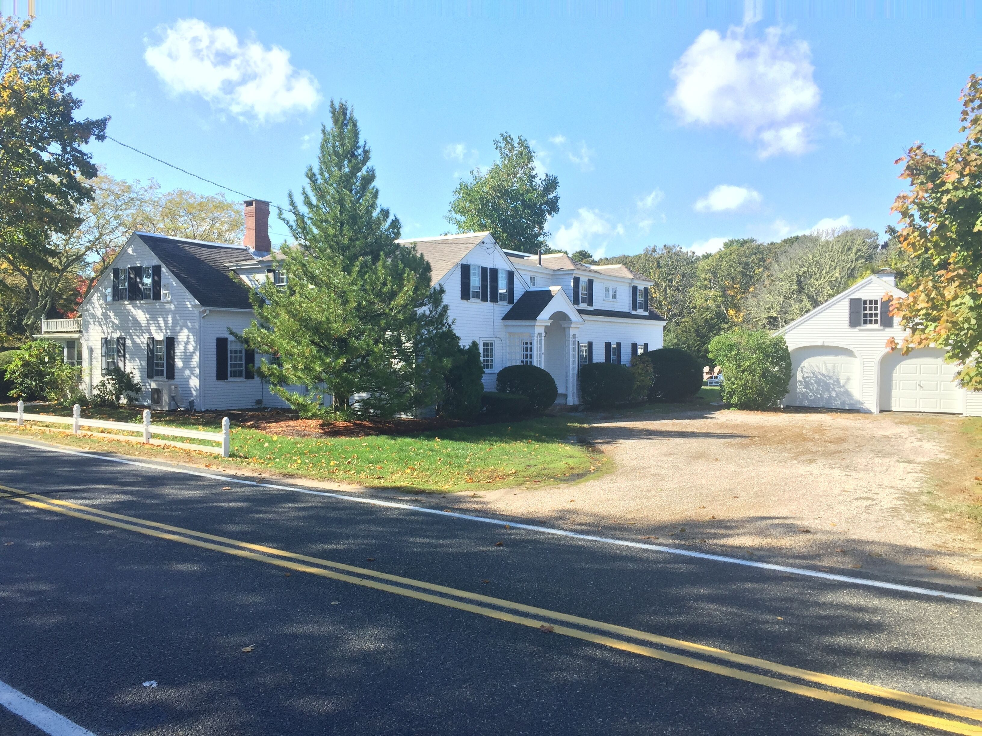 A two-story white house with a front porch, a garage, and a driveway.
