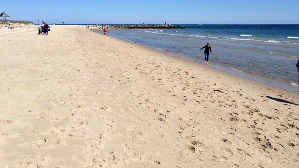 Une vaste plage de sable fin, sous un ciel bleu et dégagé.