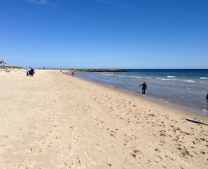 A wide sandy beach with a clear blue sky.
