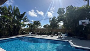 En swimmingpool med klart, blåt vand omgivet af palmer og et træhegn.