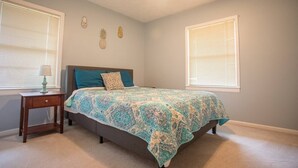 Un dormitorio con una cama, dos mesitas de noche y un ventilador de techo.