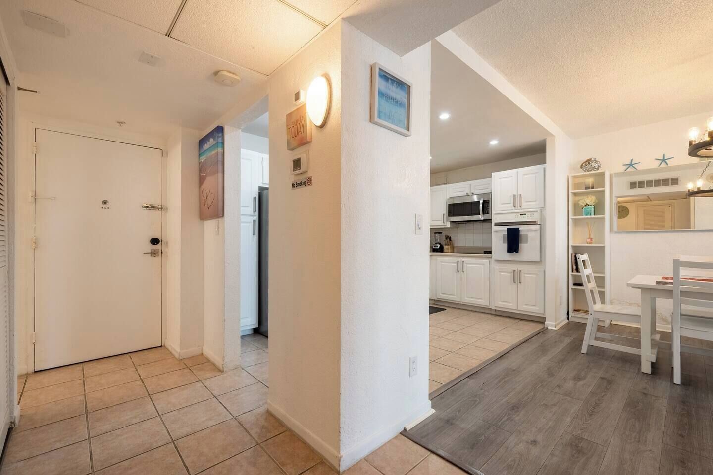A modern kitchen with white cabinets, a microwave, and a dining area with a table and chairs.