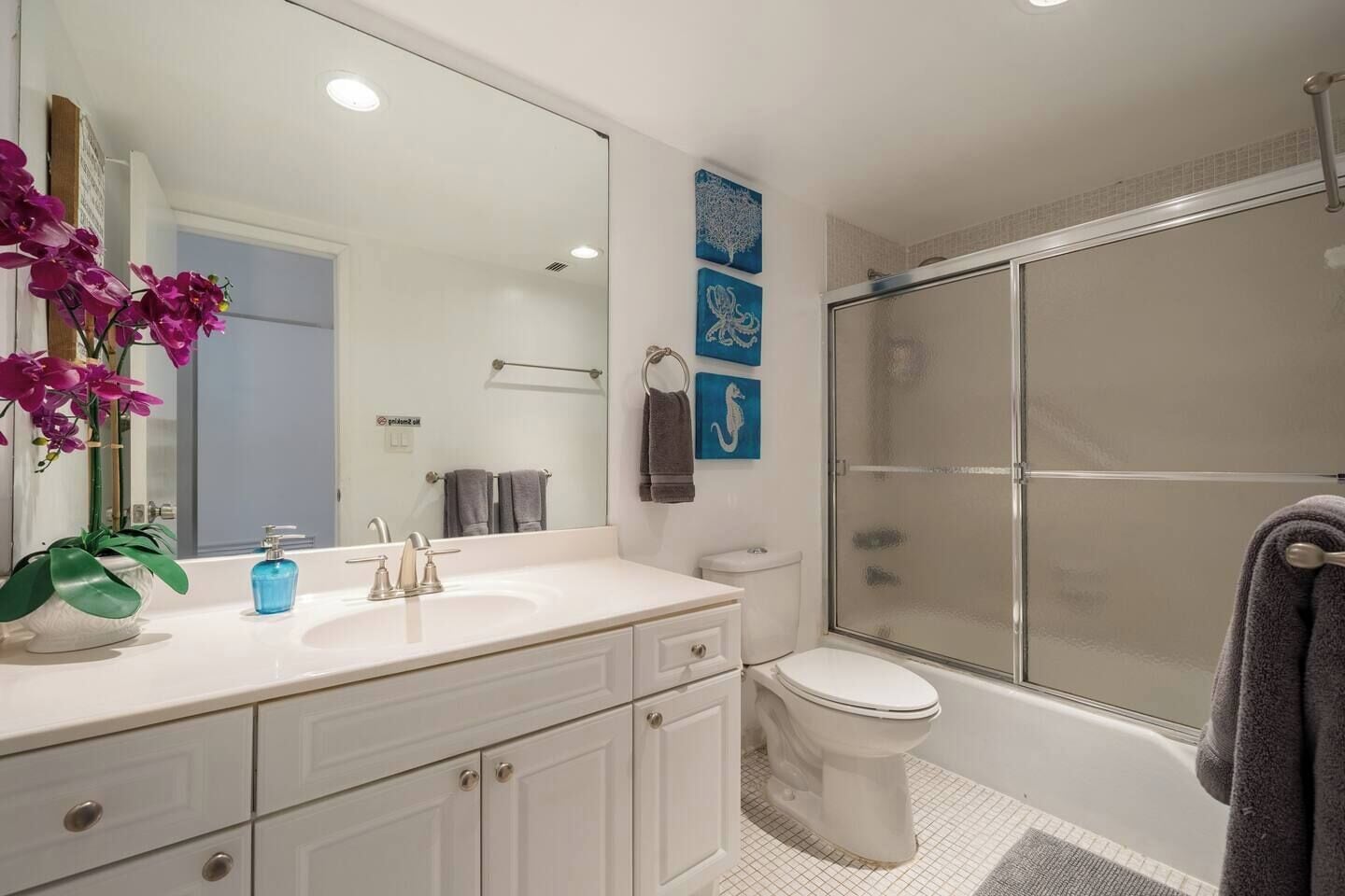 A bathroom with a white sink, a mirror, a toilet, and a shower.