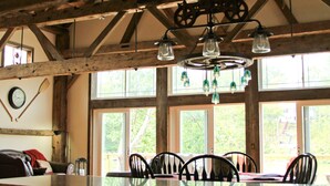 Un comedor rústico con techo de madera, ventanas amplias y una lámpara de araña.