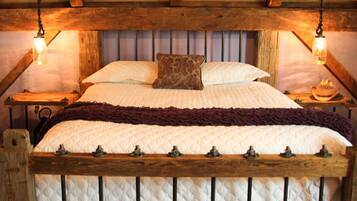 Une chambre à coucher au style rustique, avec une tête de lit en bois, une couvre-lit matelassé et deux lampes de chevet.