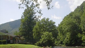 Una proprietà lungo il fiume con una casa, una zona erbosa e un pendio boscoso.