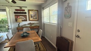 Zona pranzo con tavolo in legno, sedie, ventilatore a soffitto e camino.