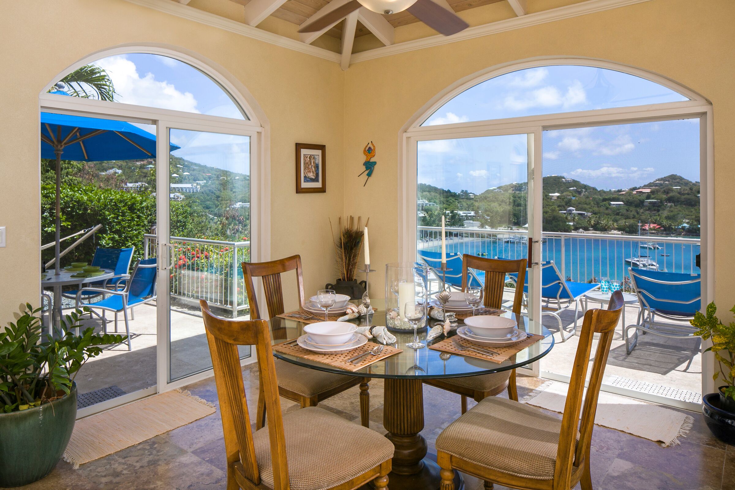 Comedor con mesa de vidrio, sillas y vista al mar y las colinas.