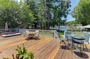 A wooden deck with outdoor furniture, a hot tub, and a view of a marina.