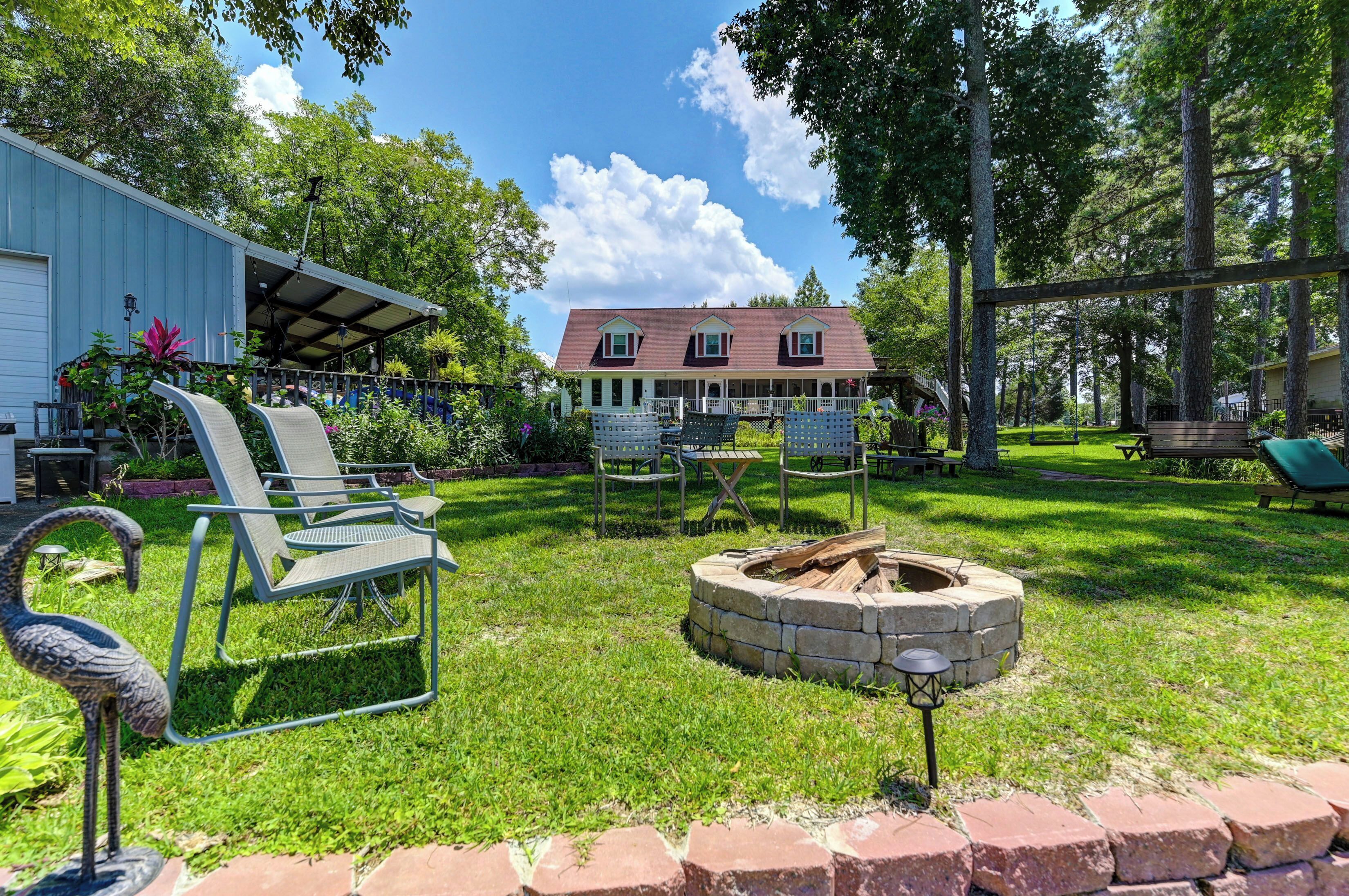 A backyard with a covered patio, outdoor seating, a fire pit, and a house in the background.