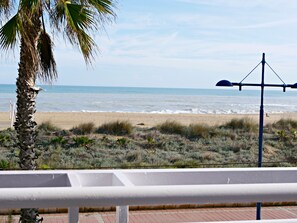 Une vue sur la plage, avec un palmier, un lampadaire et un ciel dégagé.