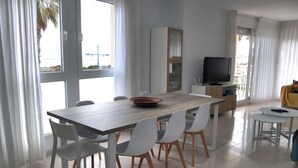A modern living room with a dining area, large windows, a flat-screen TV, and a yellow chair. - Large apartment. Front line beach, private parking, bicycles (Peñiscola)