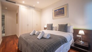 A hotel room with a large bed, a nightstand with a lamp, a wardrobe, and a framed picture on the wall. - Two bedroom apartment with terrace - You Stylish (Barcelona)