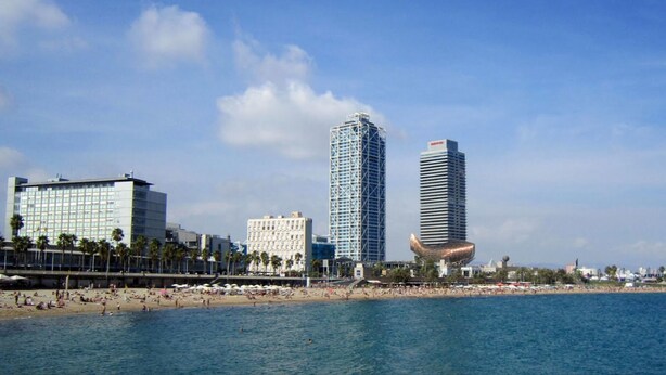A coastal cityscape with modern high-rise buildings, a beach, and a clear sky. - Two bedroom apartment with terrace - You Stylish (Barcelona)