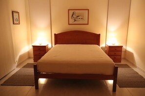 A bedroom with a wooden bed, two bedside tables with lamps, a framed picture on the wall, and a small rug on the floor. - Luxury Villa with swimming pool (Falésia)