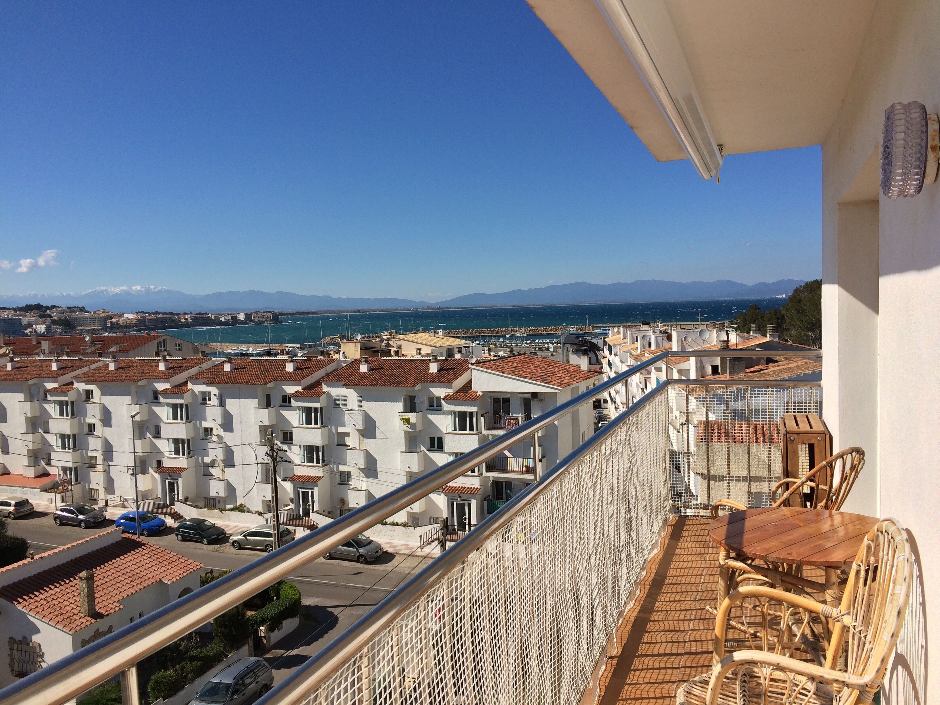 A balcony with a view of a coastal town, featuring terraced buildings and a clear sky.