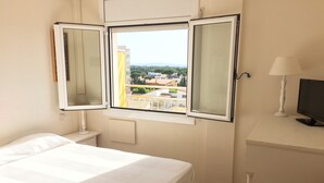 A hotel room with a bed, a desk with a lamp, a TV, and a window with an open shutter. - IMPRESSIVE VIEWS, POOL-GARDEN, CLIMATIZACION, WiFi. NEAR SEA HUTG-02835 (L´escala)