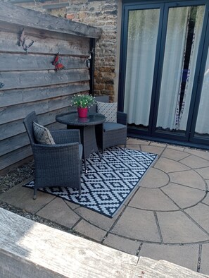 A patio area with a round table, two chairs, a potted plant, and a patterned rug. - Larch Cottage Ruston with hot tub (dogs go free) (Scarborough)