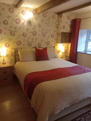 A neatly made bed with a red and white bedspread, two bedside lamps, and floral wallpaper. - Larch Cottage Ruston with hot tub (dogs go free) (Scarborough)
