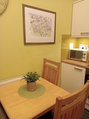 A small kitchen with a microwave, a cabinet, a framed map, and a table with a plant. - Larch Cottage Ruston with hot tub (dogs go free) (Scarborough)