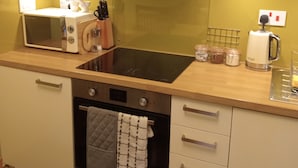 Een keuken met een fornuis, oven, magnetron en spoelbak.