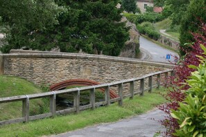 A stone bridge with a metal railing, a stone wall with a plaque, and a road curving to the right. - Larch Cottage Ruston with hot tub (dogs go free) (Scarborough)