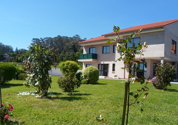 A two-story building with a red roof, surrounded by well-maintained lawns and various shrubs.