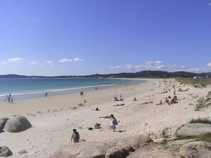 A sandy beach with people sunbathing and walking.