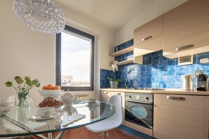 A modern kitchen with a glass dining table, a built-in oven, and blue-tiled backsplash.