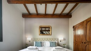 Un dormitorio con una cama grande, vigas de madera en el techo, un espejo y un armario.
