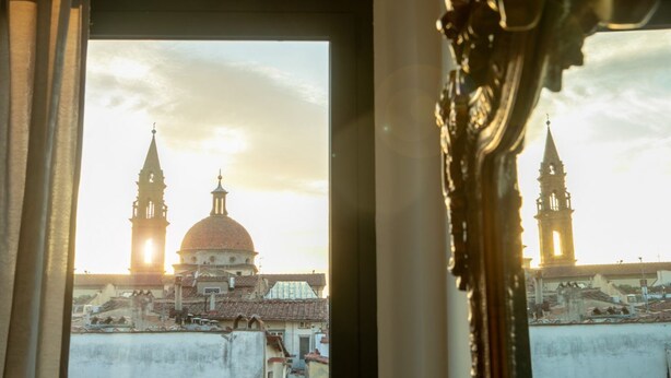 Vista a través de una ventana que muestra un edificio con cúpula y dos torres, posiblemente una construcción histórica o religiosa.