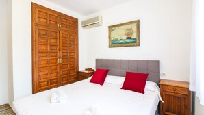 Ein Hotelzimmer mit einem großen Holzschrank, einem Bett mit weißer Bettwäsche und roten Kissen, einem Nachttisch und einem Bild eines Segelboots an der Wand.