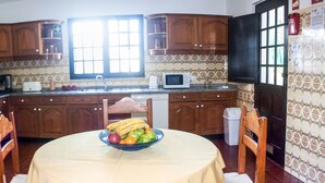 A kitchen with wooden cabinets, a microwave, and a bowl of fruit on the table. - Detached villa with private pool 1.5 km from Vilamoura marina (Vilamoura, Loule)