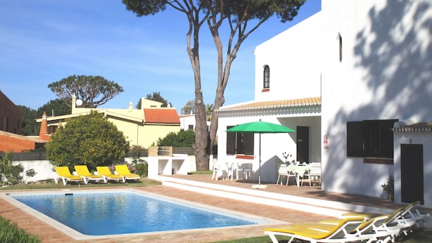 A pool area with lounge chairs, a table with chairs, and a large tree. - Detached villa with private pool 1.5 km from Vilamoura marina (Vilamoura, Loule)