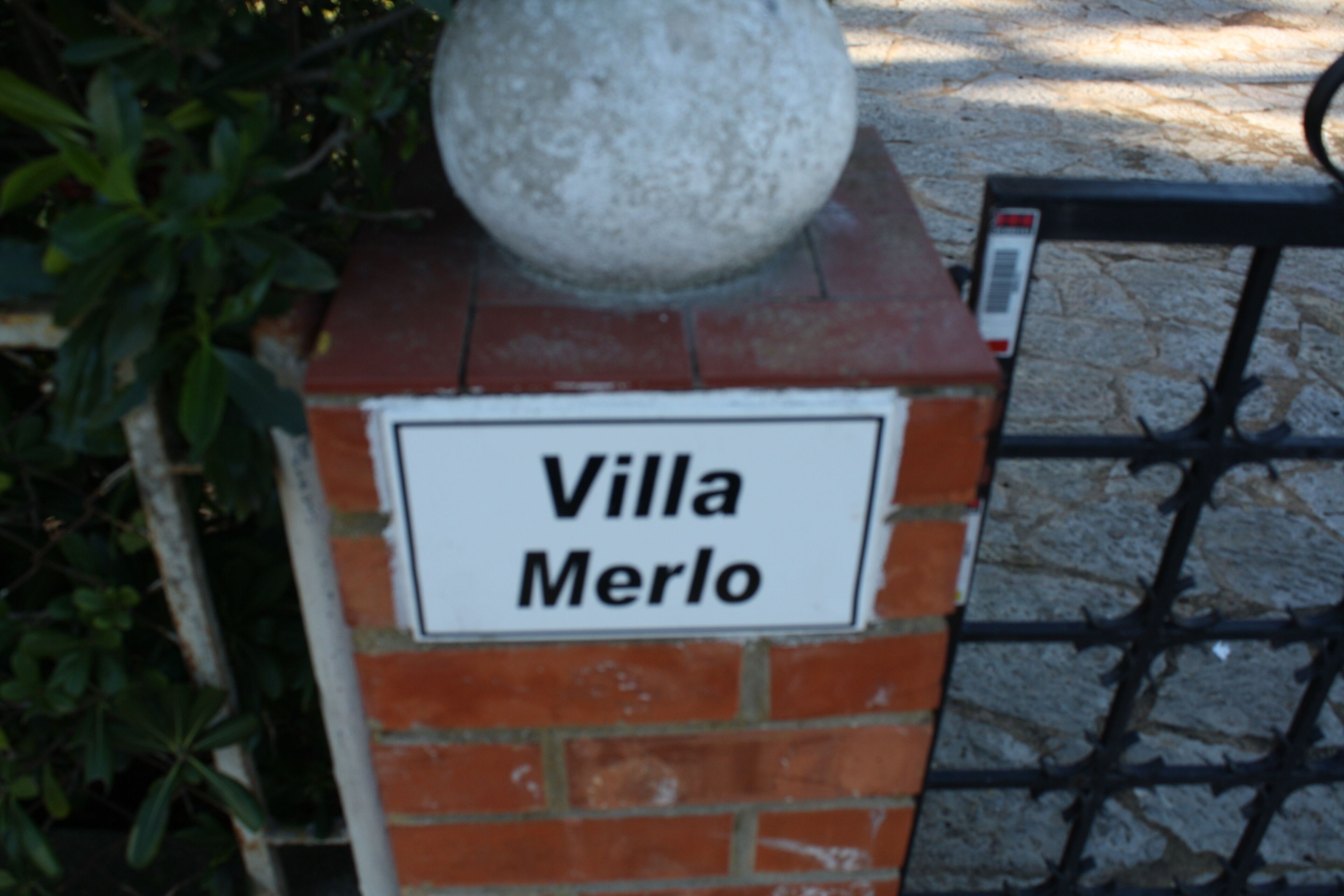 Une plaque sur un mur de briques portant l’inscription « Villa Merlo ».