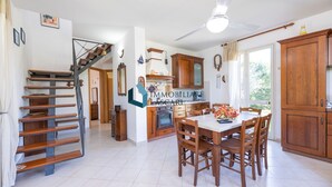 A spacious kitchen with wooden cabinets, a dining table, and a staircase. - Villa Limuti with shared swimming pool (Cefalù)