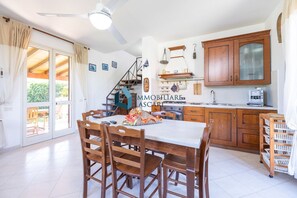 Une cuisine spacieuse avec des meubles de rangement en bois, une table à manger et un escalier menant à l’étage supérieur.