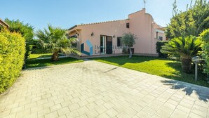 A building with a paved driveway, a well-maintained lawn, and a clear sky. - Villa Limuti with shared swimming pool (Cefalù)