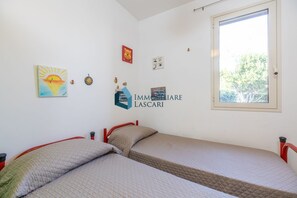A room with two beds, a window, and wall decorations including a logo and a painting.