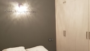 A bedroom with a bed, two pillows, a wardrobe, and a wall with a light fixture. - Nice three rooms nine modern and well equipped (agadir)