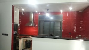 A modern kitchen with red tiles, stainless steel appliances, and a central island. - Nice three rooms nine modern and well equipped (agadir)