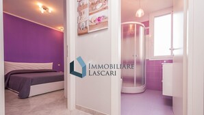 Ett modernt sovrum med en säng, ett badrum med dusch och en tydligt synlig logotyp för ”IMMOBILIARE LASCARI”.