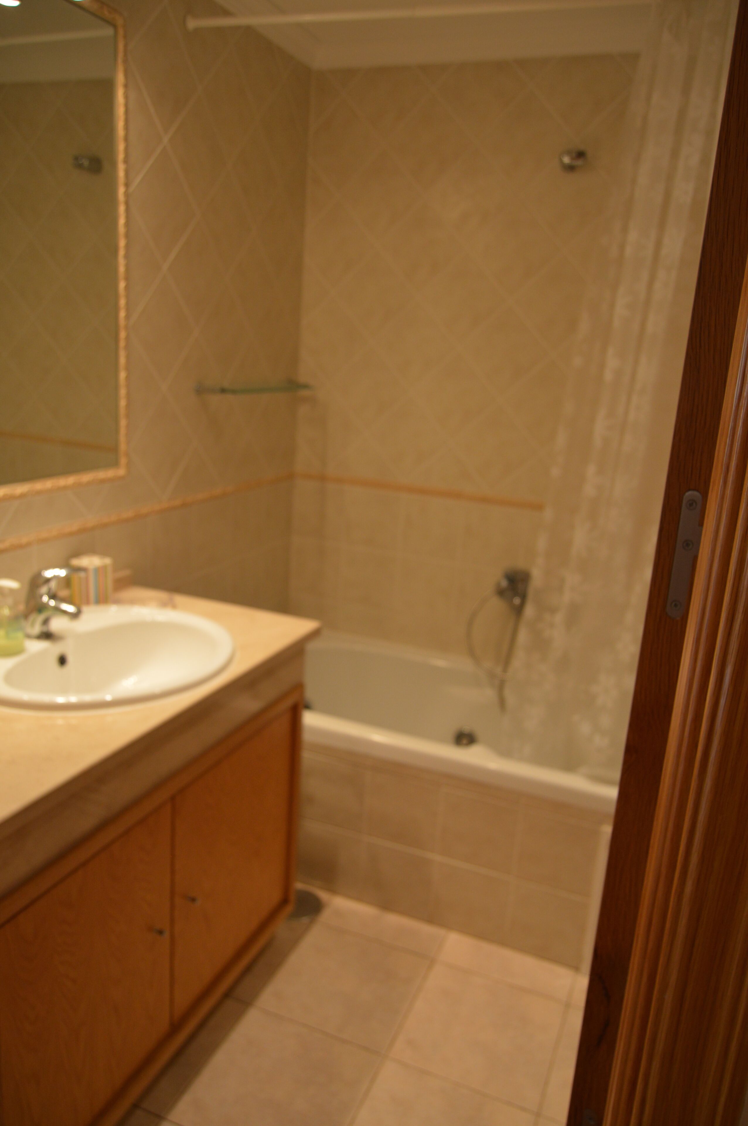 A bathroom with a sink, mirror, and bathtub.