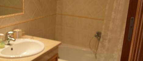 A bathroom with a sink, mirror, and bathtub.