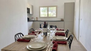 Comedor con mesa de madera dispuesta para cuatro, incluyendo platos, cubiertos y copas de vino.